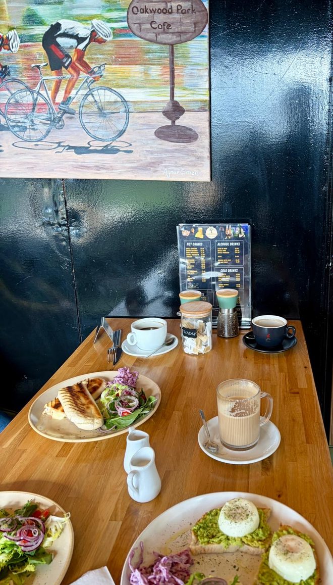 An indoor table of salads and coffees beneath cycling artwork