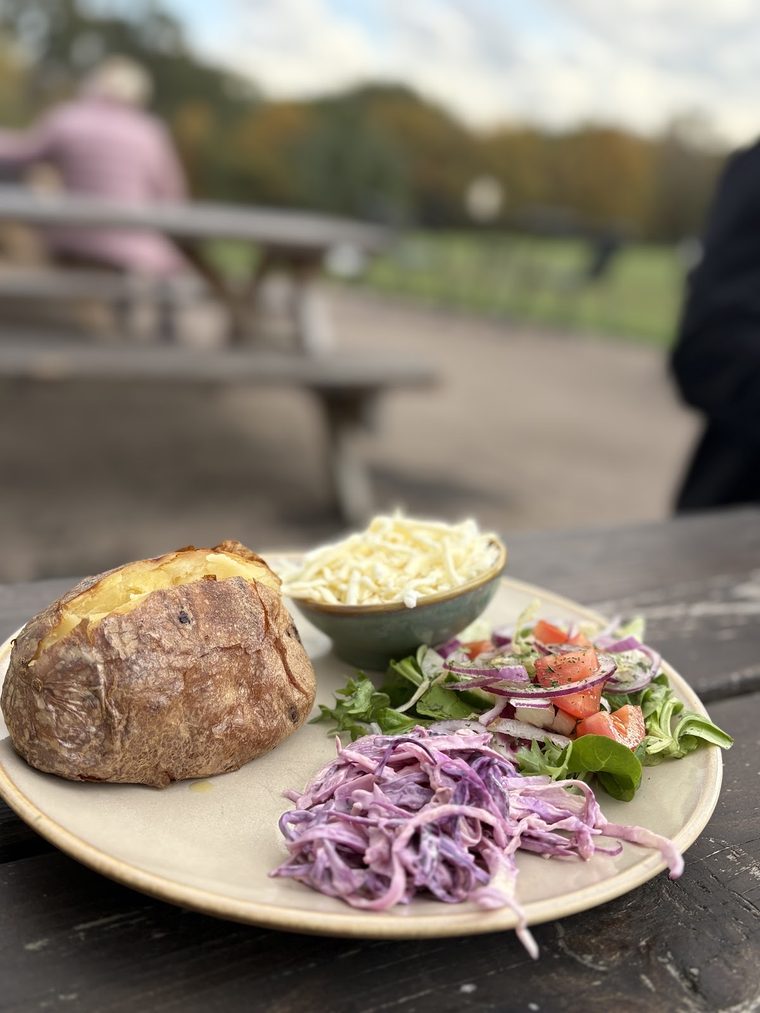 A jacket potato with cheese, coleslaw and salad